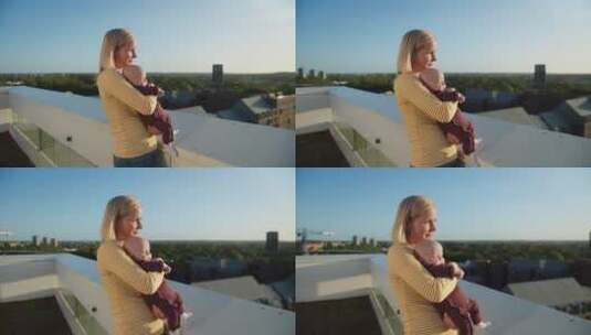 女人抱婴儿在阳台上晒太阳高清在线视频素材下载