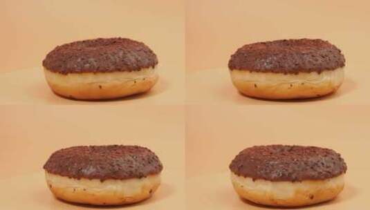 旋转巧克力甜甜圈与巧克力碎片在橙色背景。高清在线视频素材下载
